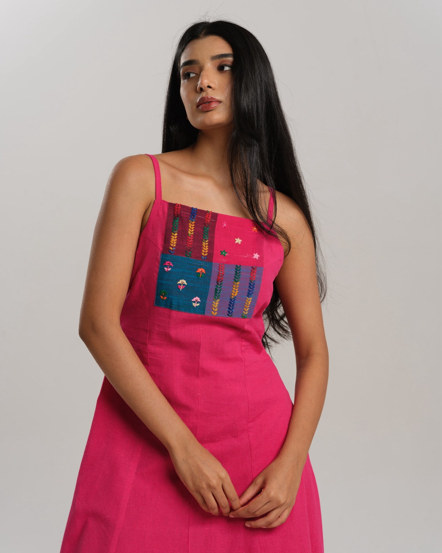 Model wearing a bright pink handwoven kurta set with colourful Ikat patchwork on the yoke, paired with straight pants.