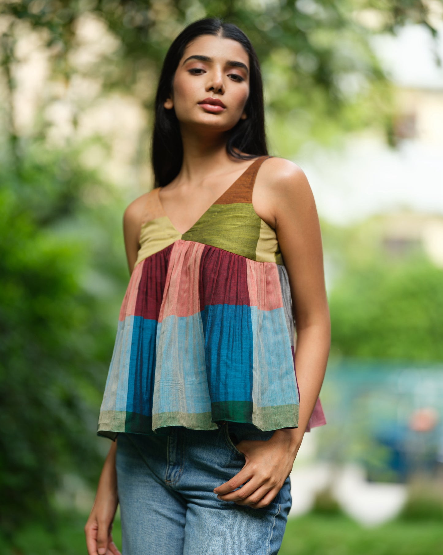 Woman wearing a handwoven Narayanpet sleeveless top with colourblocked panels, standing outdoors in natural light.