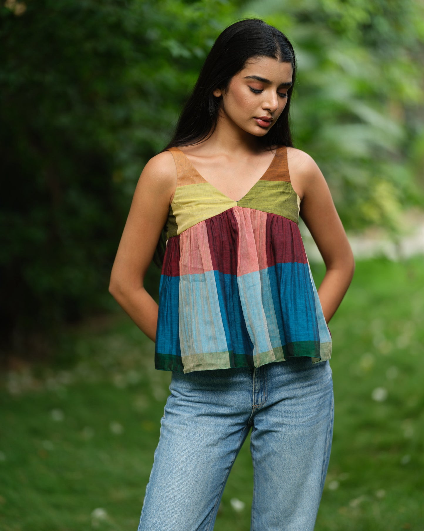 Woman wearing a handwoven Narayanpet sleeveless top with colourblocked panels, standing outdoors in natural light.