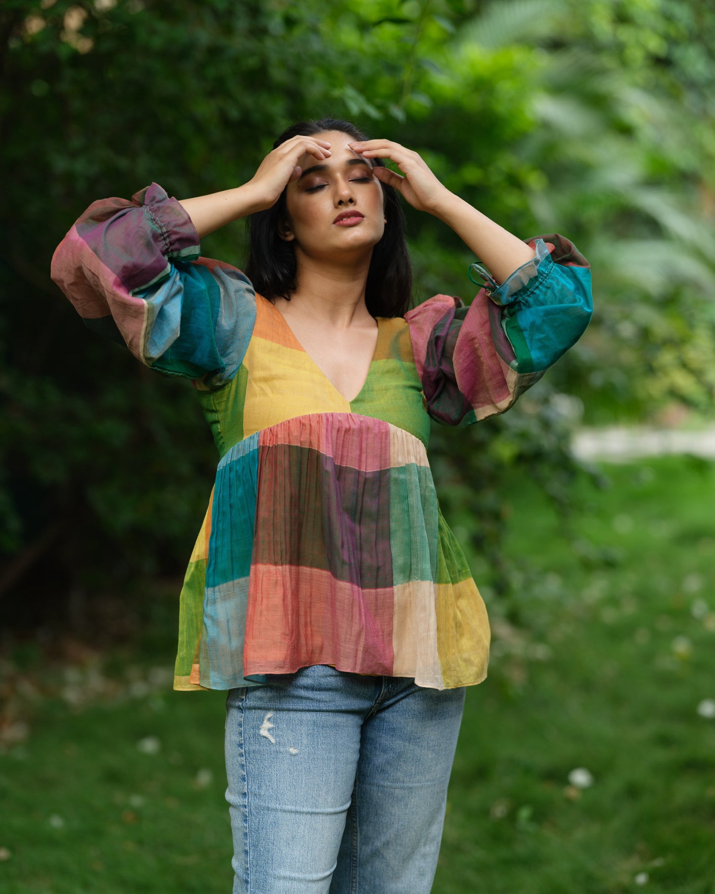 Woman wearing a multicolour Narayanpet handwoven cotton top with balloon sleeves, standing in a garden.