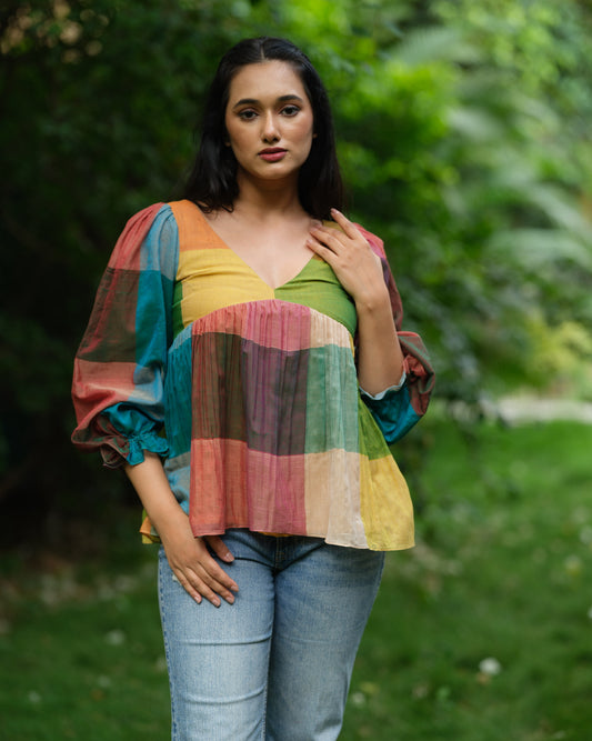 Woman wearing a multicolour Narayanpet handwoven cotton top with balloon sleeves, standing in a garden.