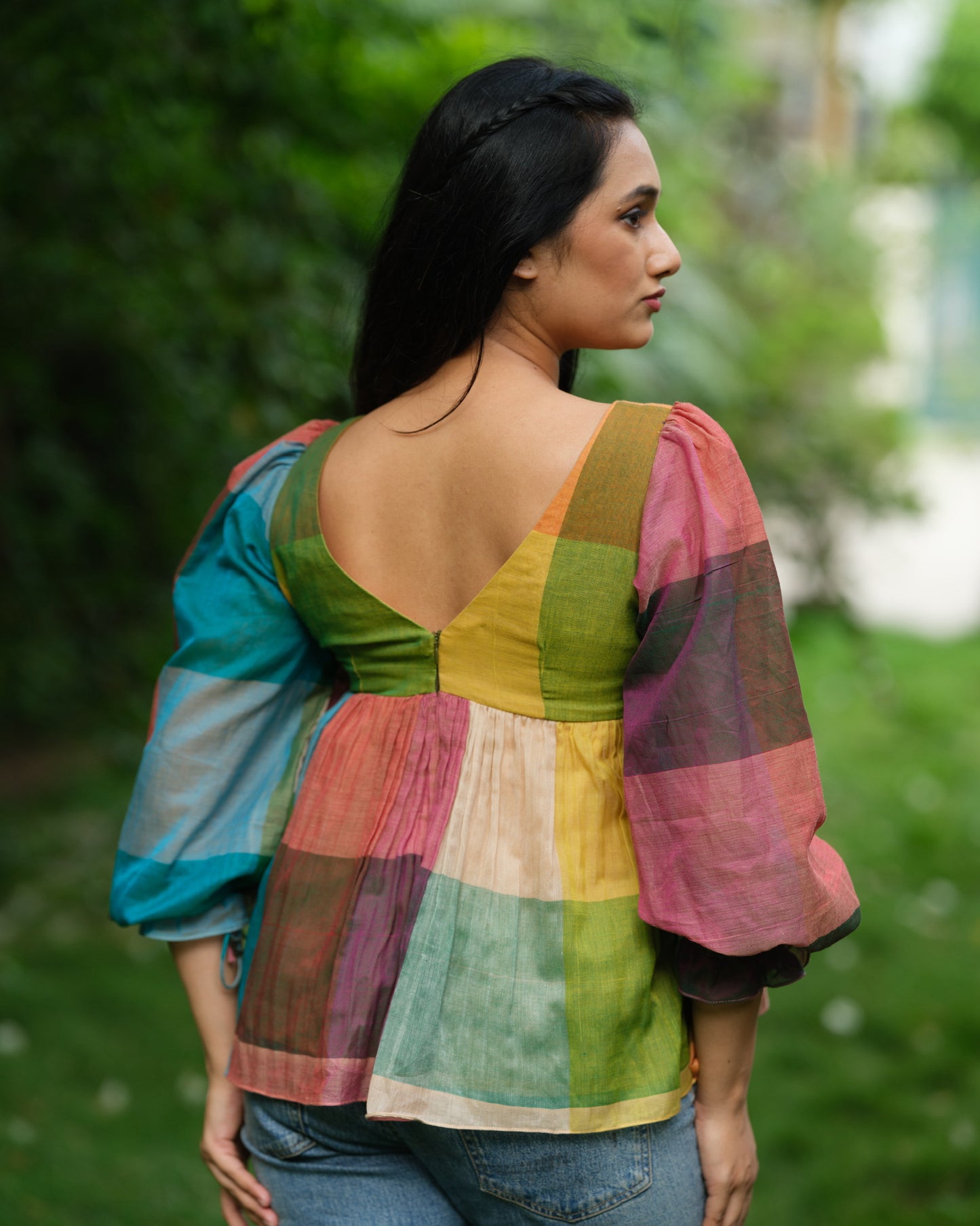 Woman wearing a multicolour Narayanpet handwoven cotton top with balloon sleeves, standing in a garden.