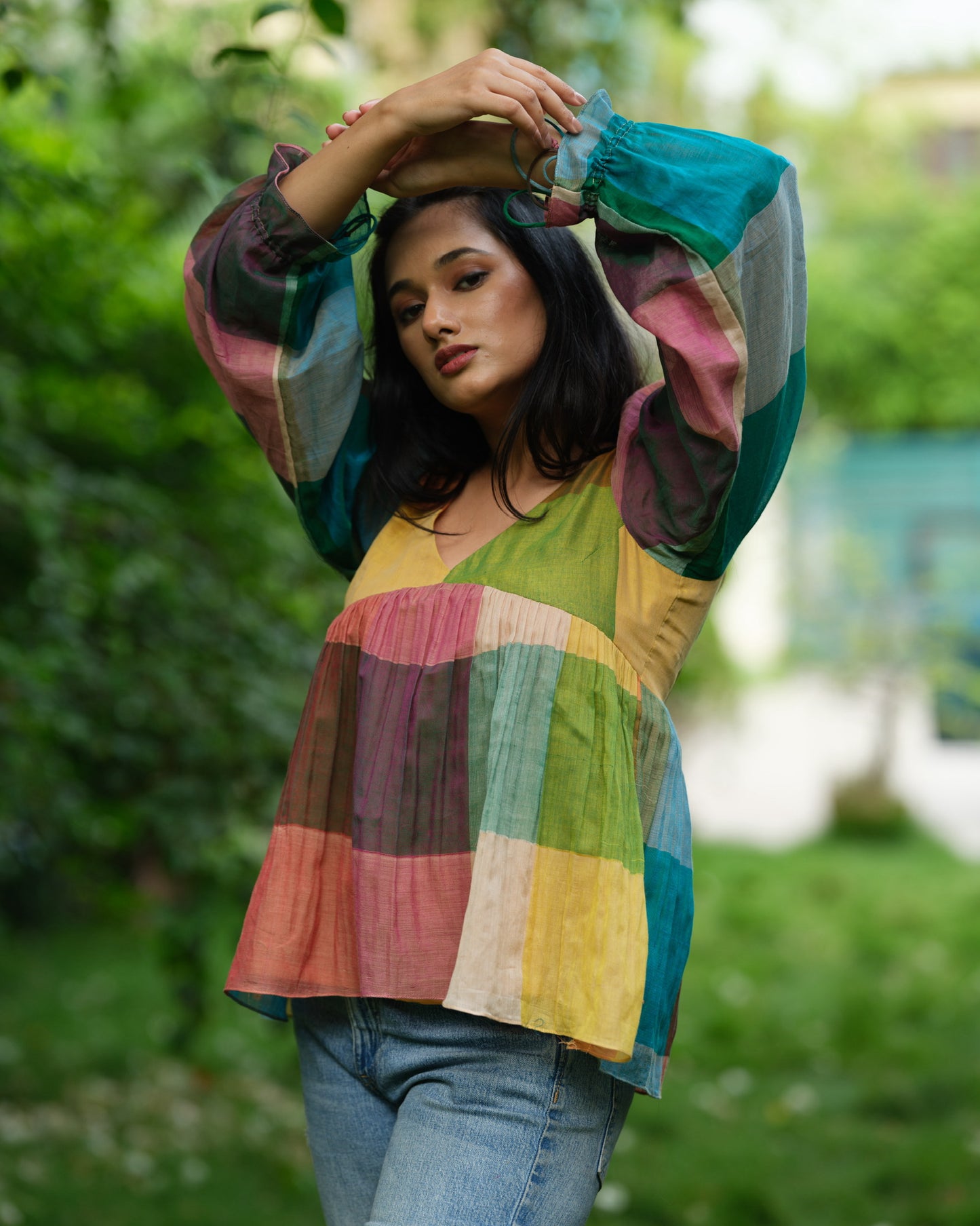 Woman wearing a multicolour Narayanpet handwoven cotton top with balloon sleeves, standing in a garden.