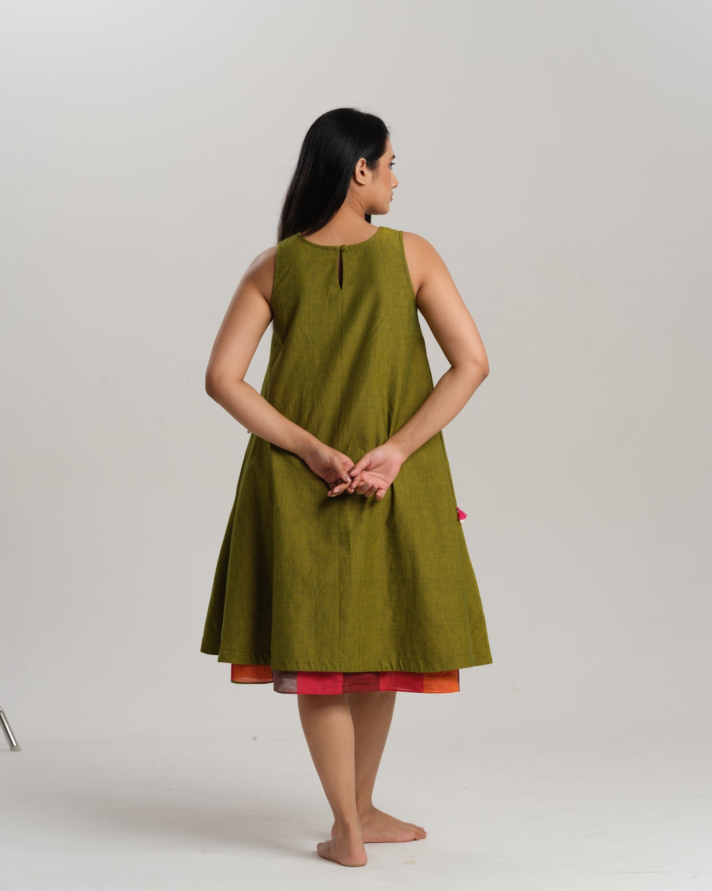Woman wearing a sleeveless lime green handwoven ikat A-line dress with vibrant patchwork, photographed in a studio setting.