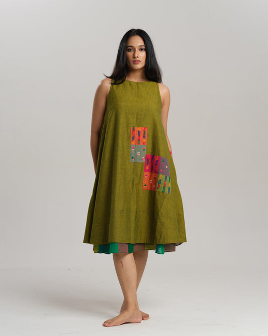 Woman wearing a sleeveless lime green handwoven ikat A-line dress with vibrant patchwork, photographed in a studio setting.