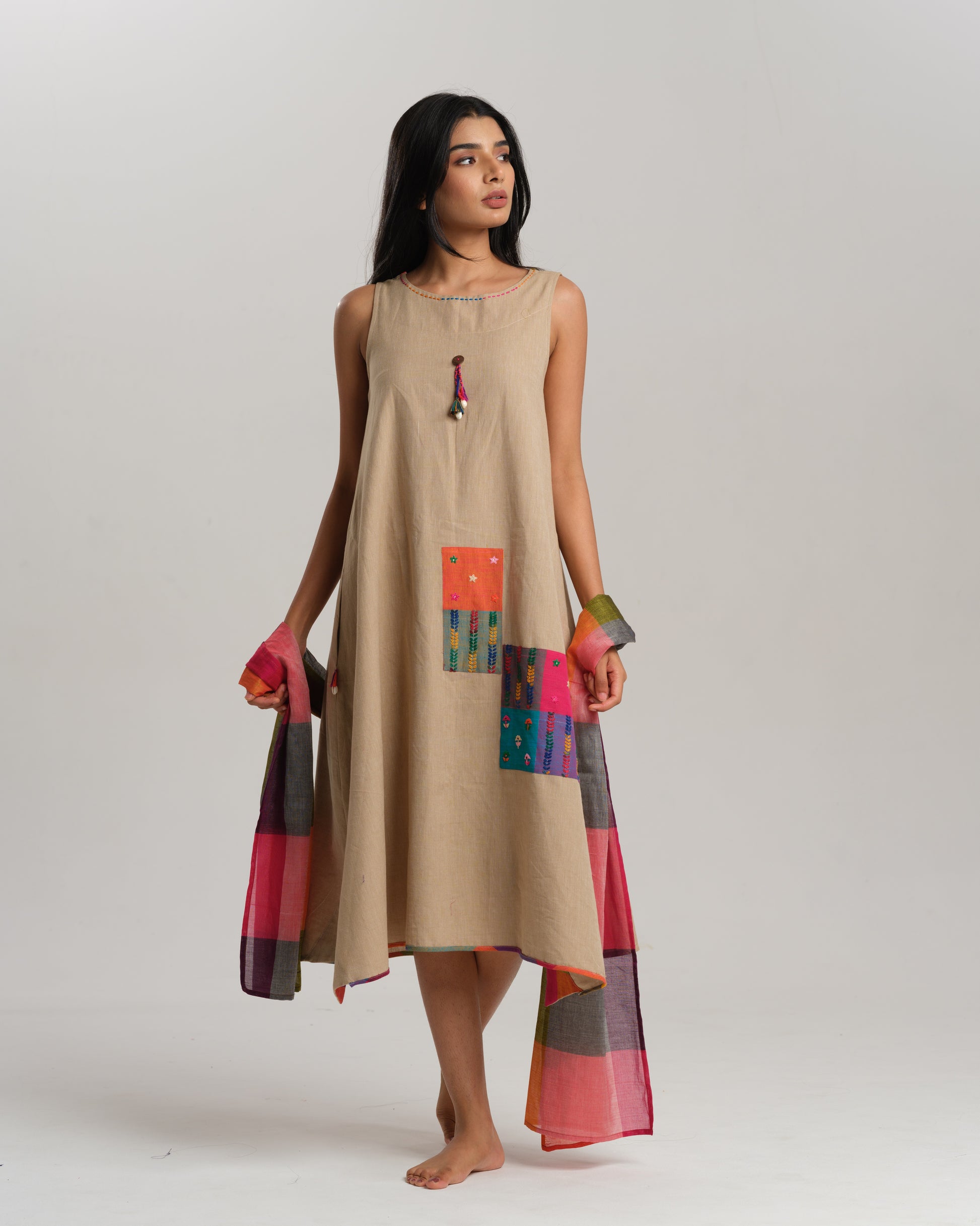 Model wearing a sleeveless beige Ikat cotton dress with colourful patchwork and Narayanpet dupatta – Ikat Rhythm dress for women by Taram.