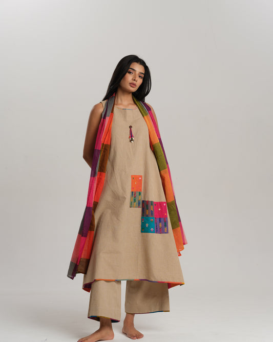 Model wearing beige sleeveless handwoven Ikat kurta set with patchwork in South Indian checks, paired with matching pants and colorful stole – Ikat Rhythm by Taram.