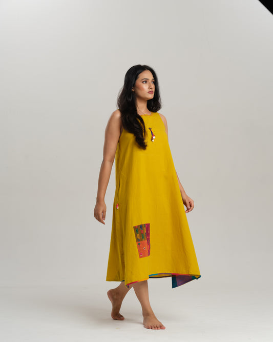 Model wearing a mustard handwoven Ikat swing dress with tassel detailing and contrast patch panels—Taram’s artisanal Sunkissed Loom dress.