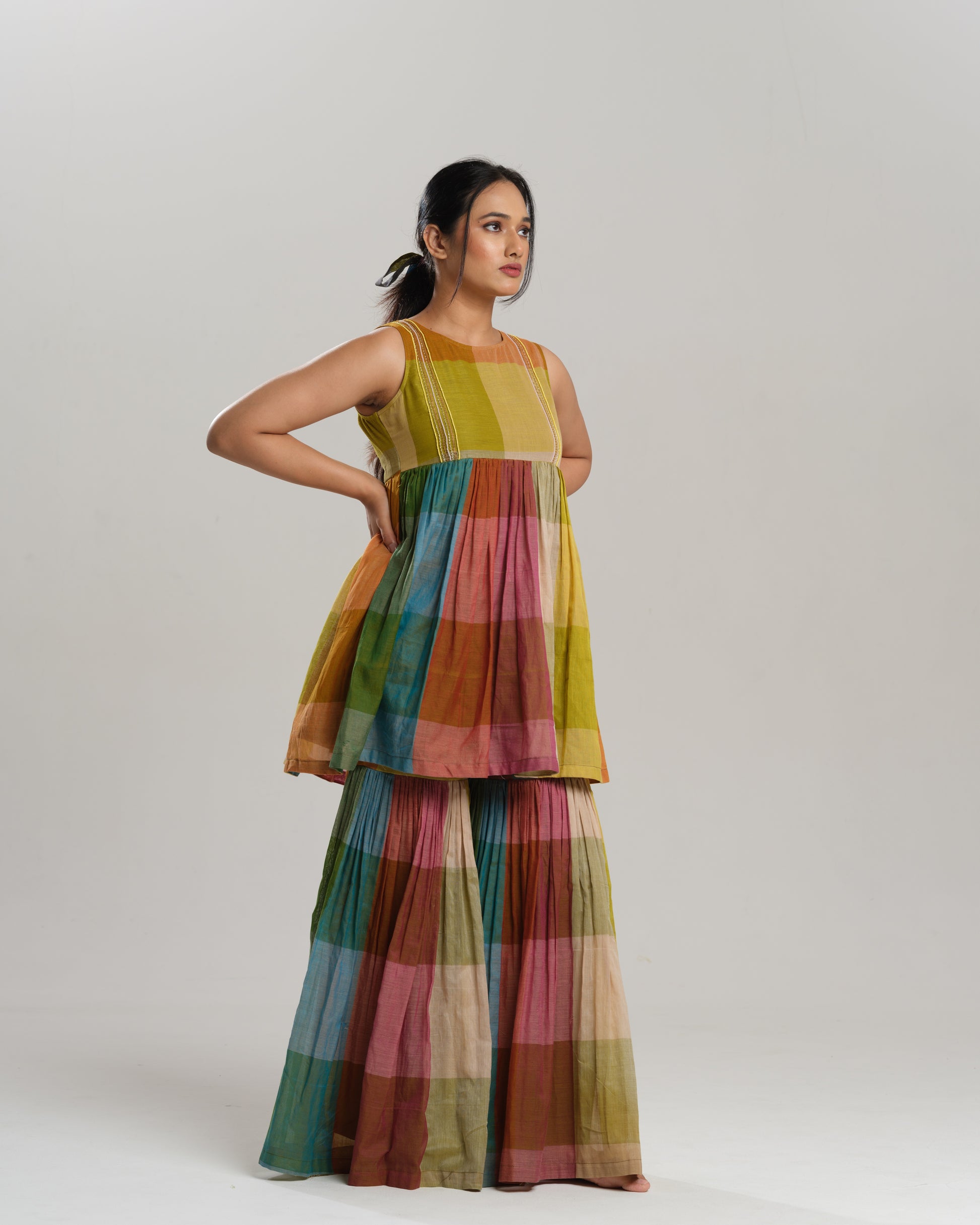 Model wearing a handwoven Narayanpet cotton sharara set in vibrant multicolour checks with embroidery detailing.
