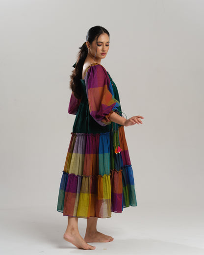 Model wearing a multicoloured handwoven Narayanpet checks cotton tiered dress with puff sleeves and mirror work bodice, styled against a minimalist background.