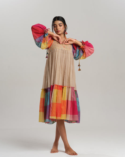Model wearing a beige cotton Narayanpet dress with colorful puff sleeves and checkered tiers – modern Indian dress for women by Taram.