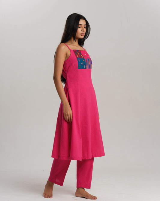 Model wearing a bright pink handwoven kurta set with colourful Ikat patchwork on the yoke, paired with straight pants.