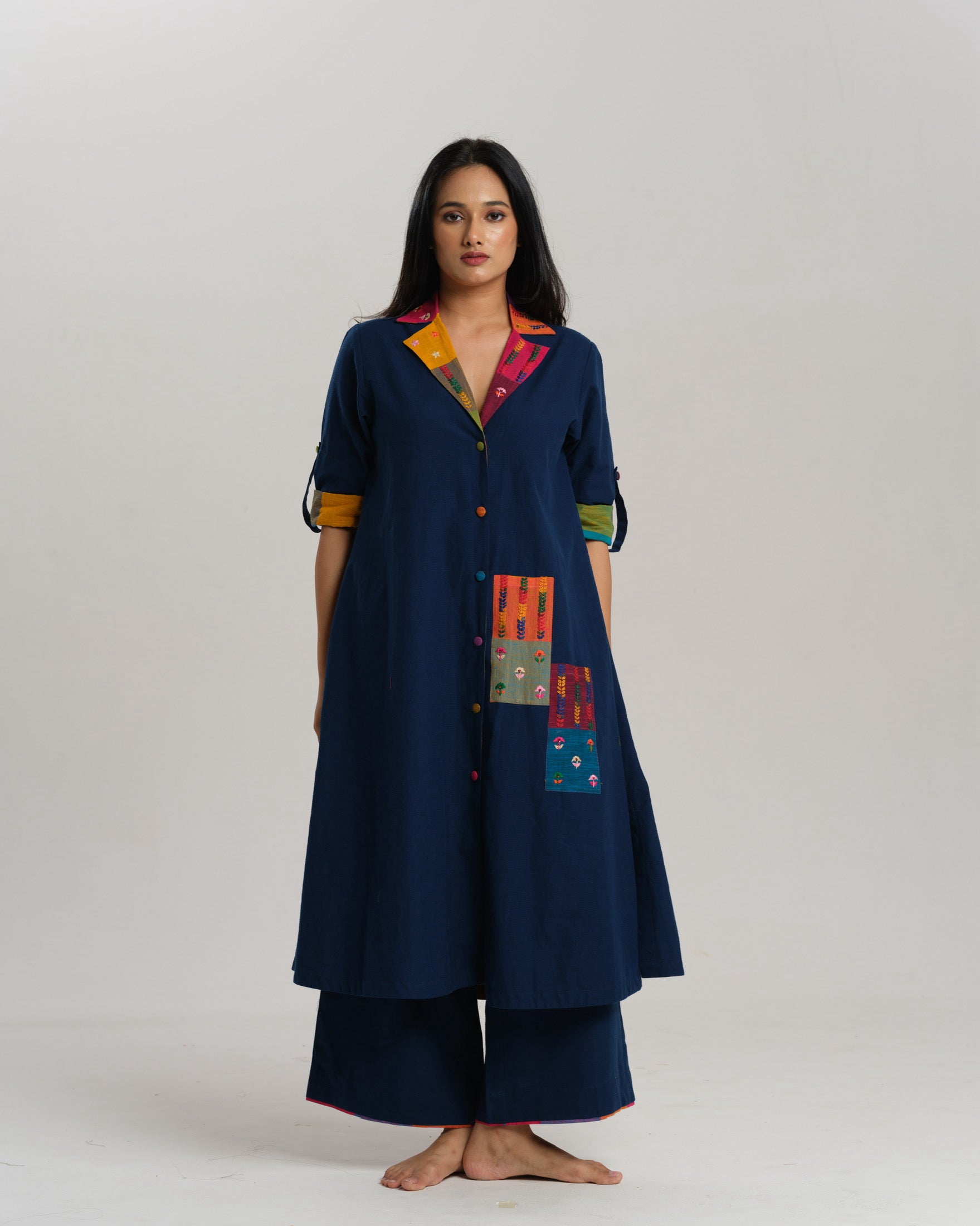 Woman wearing an indigo Ikat kurta with multicolour patch pocket and collar, standing against a neutral background.