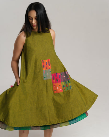 Woman wearing a sleeveless lime green handwoven ikat A-line dress with vibrant patchwork, photographed in a studio setting.