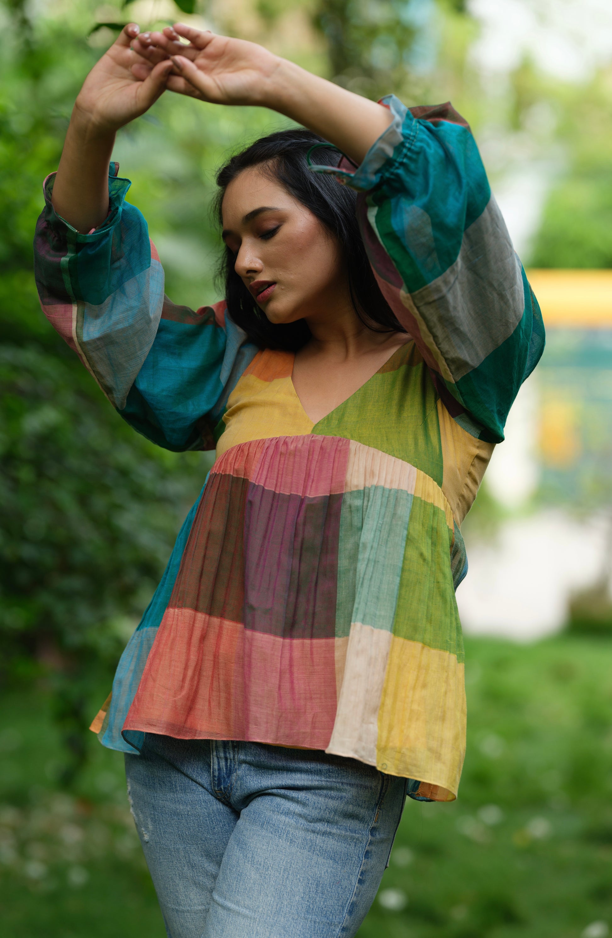 Woman wearing a multicolour Narayanpet handwoven cotton top with balloon sleeves, standing in a garden.