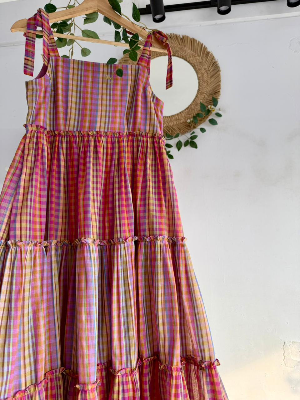 Candy Cloud Multi-Tiered Dress – pastel multicolor checked handloom dress with tie-up straps and tiered silhouette displayed on hanger.