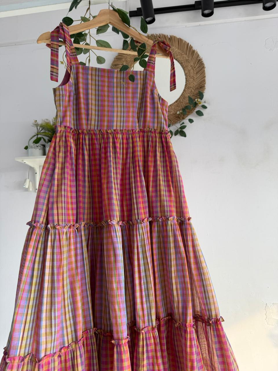Candy Cloud Multi-Tiered Dress – pastel multicolor checked handloom dress with tie-up straps and tiered silhouette displayed on hanger.