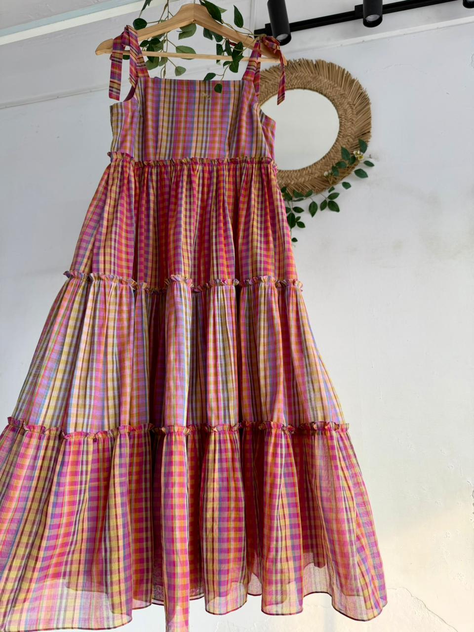 Candy Cloud Multi-Tiered Dress – pastel multicolor checked handloom dress with tie-up straps and tiered silhouette displayed on hanger.