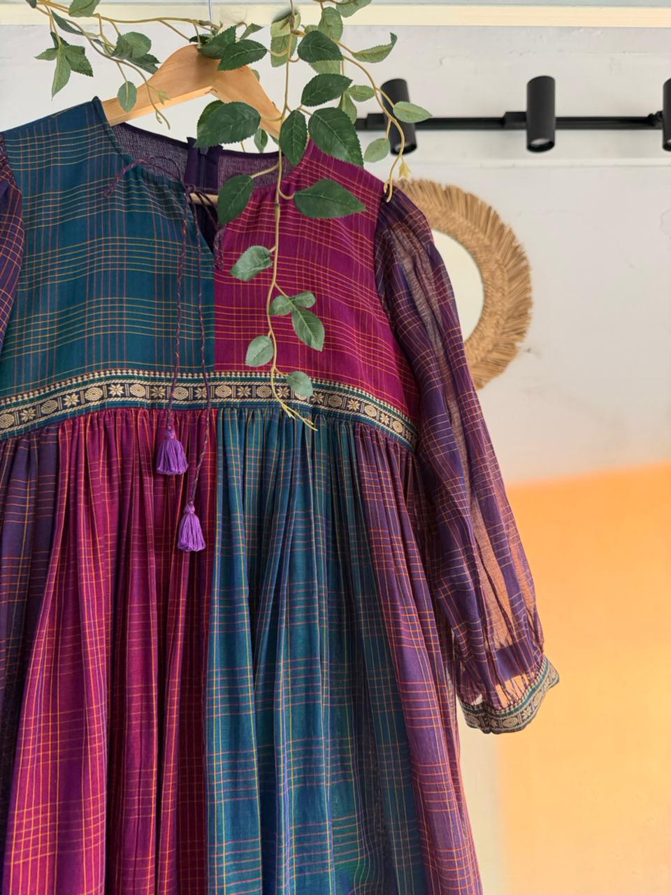 Queen’s Palette Narayanpet Dress – multi-hued handloom cotton dress in purple, magenta, and teal with zari borders, displayed on hanger.